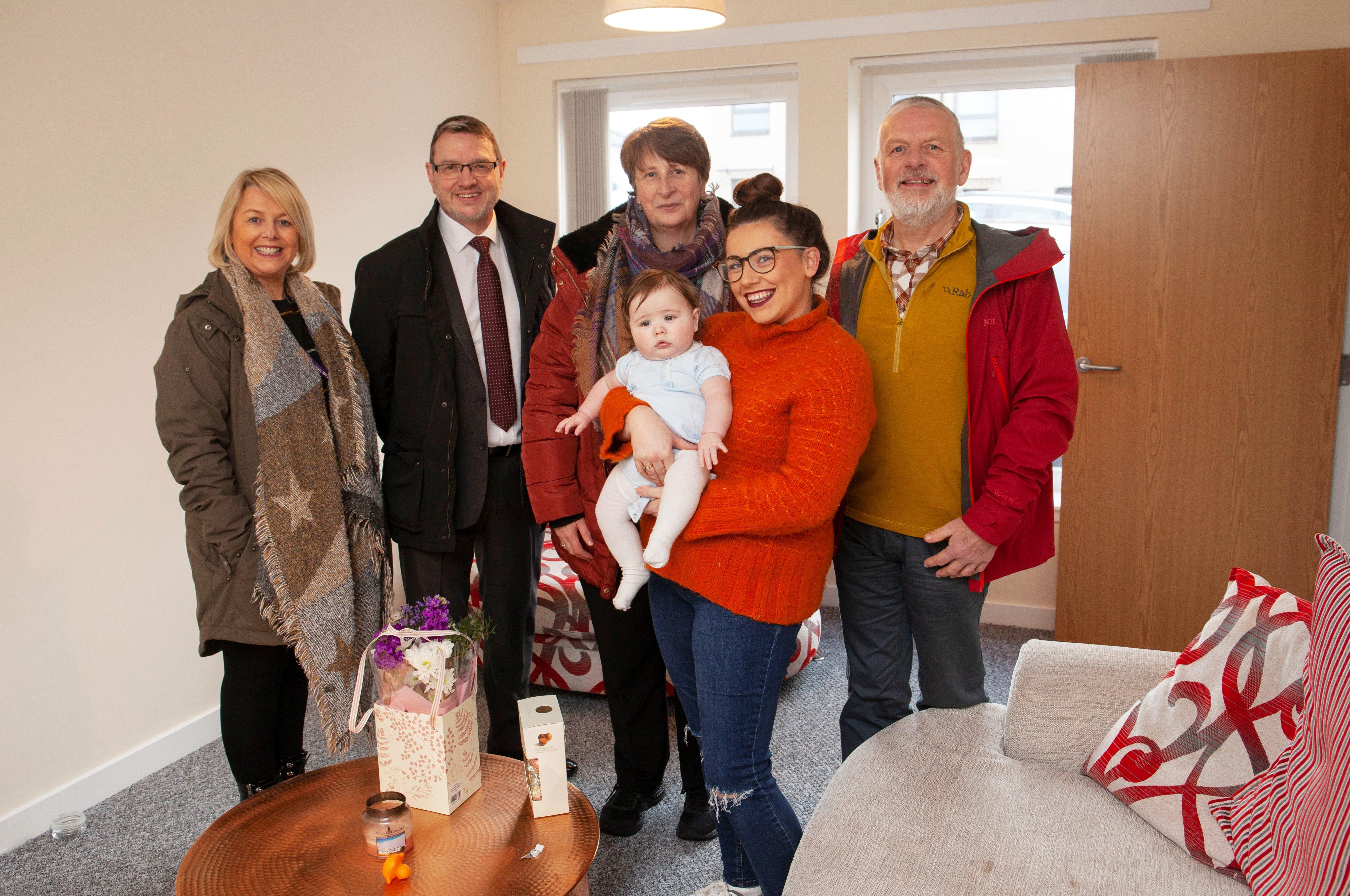 New tenants Sarah O’Donnell and baby Darragh in their new home with the Oak Tree team (from left), Julie McEwan, Senior Housing Officer; Hazel Aitken, Housing Manager (red jacket); Brian Praties, Development/Technical Services Manager; and Chairperson, Colin Campbell.